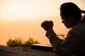 Silhouette of woman kneeling down praying for worship God at sky background. Christians pray to jesus christ for calmness. In Royalty Free Stock Photo