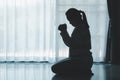 silhouette of woman kneeling and praying in modern church at sunset time. Female catholic prayer worship to God wish a better life Royalty Free Stock Photo