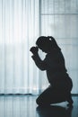 silhouette of woman kneeling and praying in modern church at sunset time. Female catholic prayer worship to God wish a better life Royalty Free Stock Photo