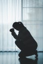 silhouette of woman kneeling and praying in modern church at sunset time. Female catholic prayer worship to God wish a better life Royalty Free Stock Photo