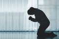 silhouette of woman kneeling and praying in modern church at sunset time. Female catholic prayer worship to God wish a better life Royalty Free Stock Photo