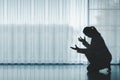 silhouette of woman kneeling and praying in modern church at sunset time. Female catholic prayer worship to God wish a better life Royalty Free Stock Photo