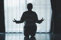 silhouette of woman kneeling and praying in modern church at sunset time. Female catholic prayer worship to God wish a better life Royalty Free Stock Photo