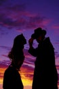 Silhouette of woman leaning toward cowboy in sunset Royalty Free Stock Photo