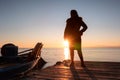 Silhouette of a woman looking at the horizon against the sunlight on a jetty of a lake at sunset Royalty Free Stock Photo