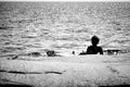 Silhouette of woman lying on a rock in the ocean.