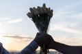 Silhouette of woman and man holding in their hands a bouquet of white tulips flowers against sunset beach. Royalty Free Stock Photo