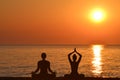 Silhouette of woman and man practicing yoga on the beach Royalty Free Stock Photo