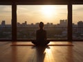 Silhouette of a woman meditating on a wooden floor.