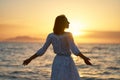 Silhouette of woman with open arms standing at beach, enjoying orange sundown over the ocean Royalty Free Stock Photo