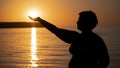 Silhouette of a woman with an outstretched arm. Sunset