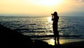 Silhouette of a woman photographer on a beach at sunrise. Royalty Free Stock Photo