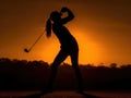 Silhouette of a woman playing golf at sunset