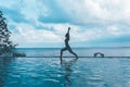 Silhouette woman practice yoga Warrior one pose to meditation summer vacation on the pool above the beach Royalty Free Stock Photo