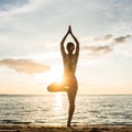 Silhouette of a woman practicing the tree yoga pose on a beach a Royalty Free Stock Photo