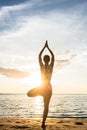 Silhouette of a woman practicing the tree yoga pose on a beach Royalty Free Stock Photo