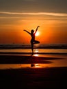 Silhouette of a woman practicing yoga on the beach at sunset. Morning natural stretch warm-up training. Royalty Free Stock Photo