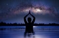 Woman practicing yoga lotus pose in infinity swimming pool under a starry sky with milky way arch Royalty Free Stock Photo