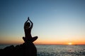 Silhouette of woman practicing yoga during soft amazing sunset on beach Royalty Free Stock Photo