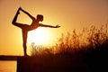 Silhouette woman practicing yoga or stretching on the beach pier at sunset or sunrise Royalty Free Stock Photo