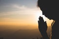 Silhouette of a woman Praying hands with faith in religion and belief in God On the morning sunrise background. Namaste or