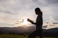 Silhouette of woman praying to god with bible on mountain at sunset background. Woman raising his hands in worship. Christian Royalty Free Stock Photo