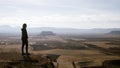 Silhouette of a woman in profile observing the arid desert plain from the top. Desert with gully mountains and sandstone plateaus