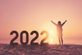 Silhouette woman raise hand up and number 2022 at tropical beach on sunset sky abstract background. Happy new year and holiday Royalty Free Stock Photo