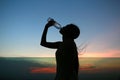 Silhouette of woman Rehydrate and refresh at sunset