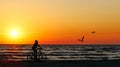 Silhouette of a woman rides a bike at sunset. The Baltic sea Royalty Free Stock Photo