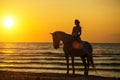 Silhouette of a woman riding a horse on the beach at sunset