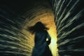 A silhouette of a woman running, fleeing from something, through a tunnel. View from behind. AI generated image