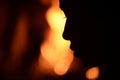 Silhouette of a woman`s face against the background of a burning fire in the fireplace