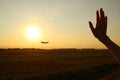 Silhouette of woman`s hand waving to the airplane against sunset sky Royalty Free Stock Photo