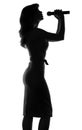 Silhouette of a woman singing with a microphone in hands Royalty Free Stock Photo