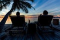 Silhouette woman sit on beach chair drinking cocktail watching s