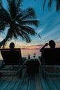 Silhouette woman sit on beach chair having cocktail drink watching sunset over the sea.