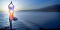 Silhouette of woman sits in a otus pose on beach sunset view, glowing seven all chakra. Kundalini energy. girl practicing yoga Royalty Free Stock Photo