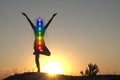 Silhouette of woman sits in a Upward Salute pose on beach sunset view, glowing seven all chakra. Kundalini energy. girl practicing Royalty Free Stock Photo