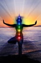 Silhouette of woman sits in a Upward Salute pose on beach sunset view, glowing seven all chakra. Kundalini energy. girl practicing Royalty Free Stock Photo