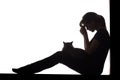 Silhouette of a woman sitting on the floor on a white isolated background with a cat in her arms, a sad girl praying Royalty Free Stock Photo