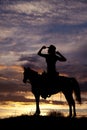 Silhouette of a woman sitting on a saddle hands on hat Royalty Free Stock Photo
