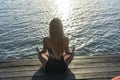 Silhouette of woman sitting at yoga pose on the tropical beach during sunset. Girl practicing yoga near sea water Royalty Free Stock Photo