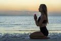 Silhouette of woman sitting at yoga pose on the tropical beach during sunset. Girl practicing yoga near sea water Royalty Free Stock Photo