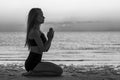 Silhouette of woman sitting at yoga pose on the tropical beach during sunset. Girl practicing yoga near sea water. Black and white Royalty Free Stock Photo