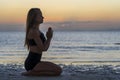 Silhouette of woman sitting at yoga pose on the tropical beach during sunset. Girl practicing yoga near sea water Royalty Free Stock Photo