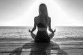 Silhouette of woman sitting at yoga pose on the tropical beach during sunset. Girl practicing yoga near sea water Royalty Free Stock Photo