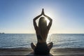 Silhouette of woman sitting at yoga pose on the tropical beach during sunset. Girl practicing yoga near sea water Royalty Free Stock Photo