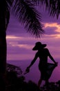 Silhouette of a woman in a skirt and hat hold sandles back