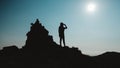 Silhouette of woman standing on rock near the edge of mountain on background of sky Royalty Free Stock Photo